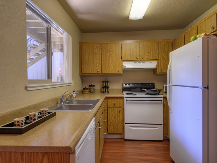 Sink, Wood Cabinets, Dishwasher, Woodinspired Floor, Open Window and Refrigerator/Freezer